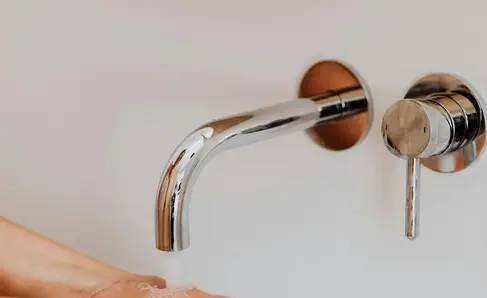 a person washing their hands under a faucet