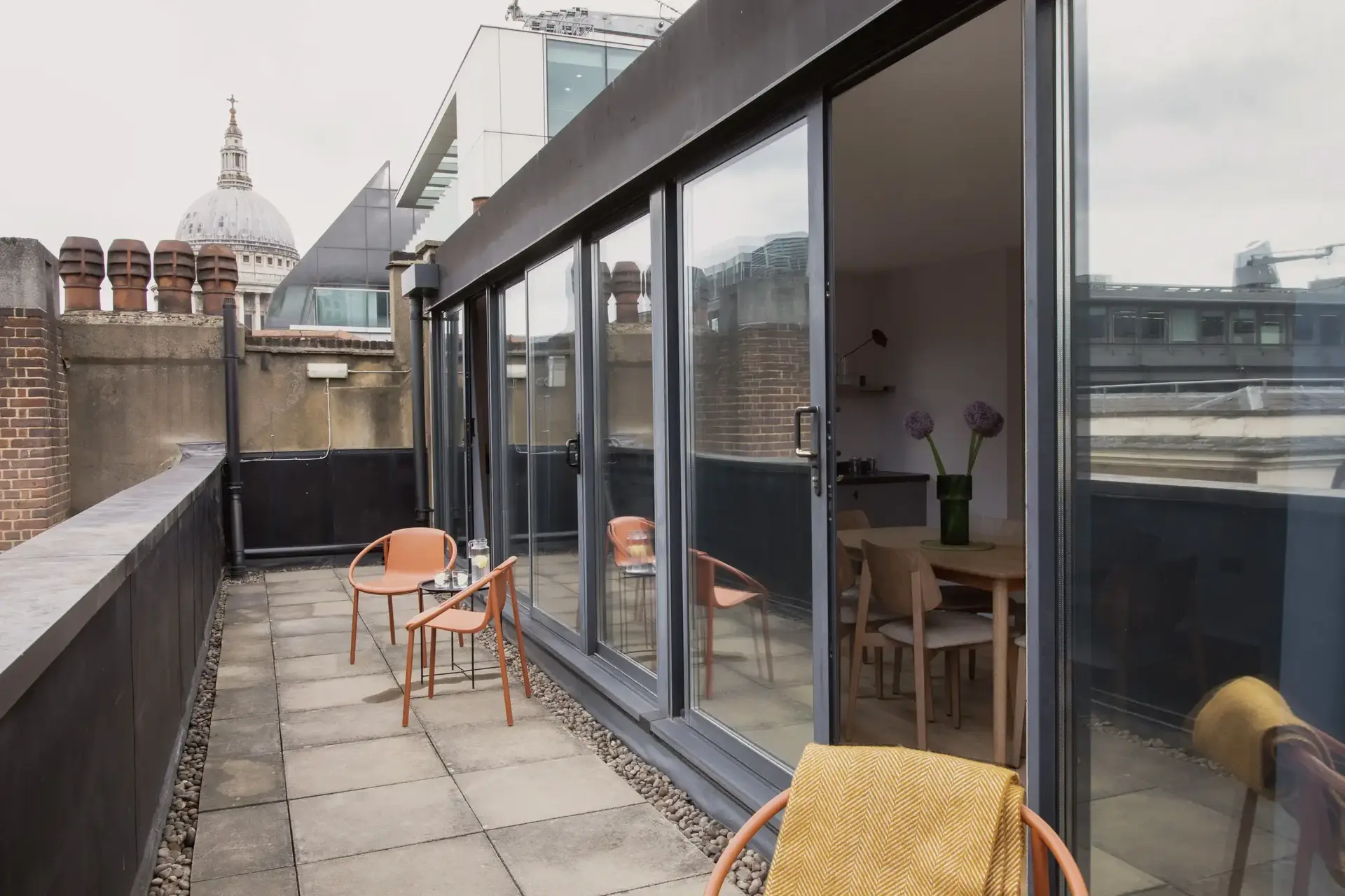 a patio with chairs and table on a rooftop